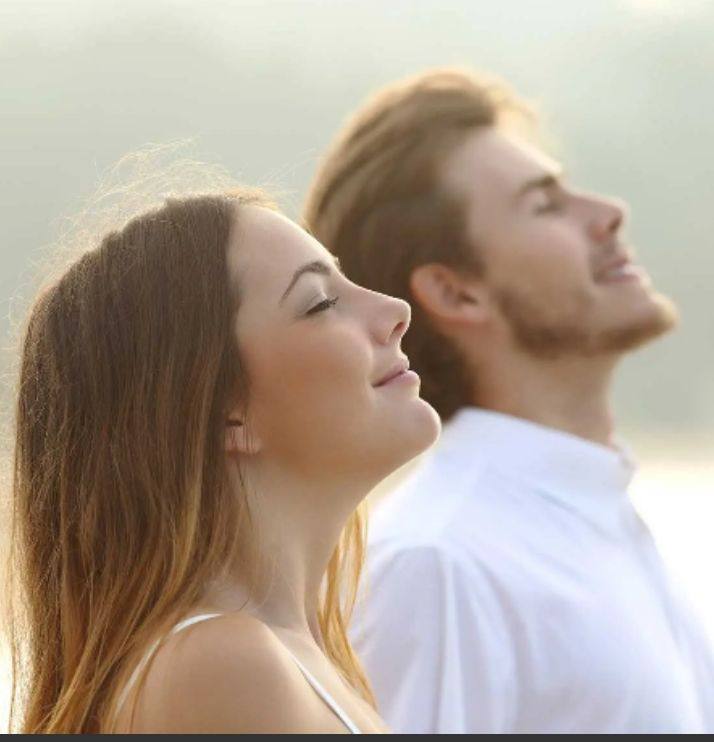 Due persone a occhi chiusi respirano profondamente all'aria aperta